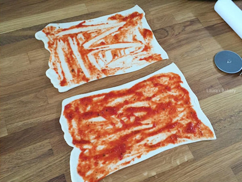 Tomato sauce spread over pizza dough