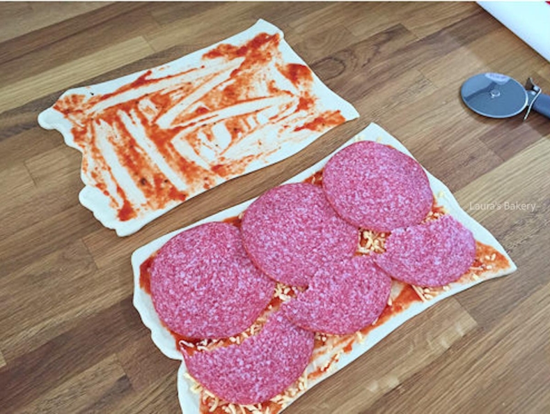 Salami slices loaded onto pizza dough