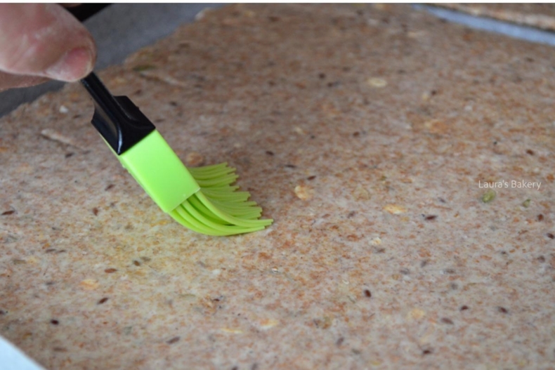 Spelt seed cracker dough rolled out on a parchment-lined baking sheet