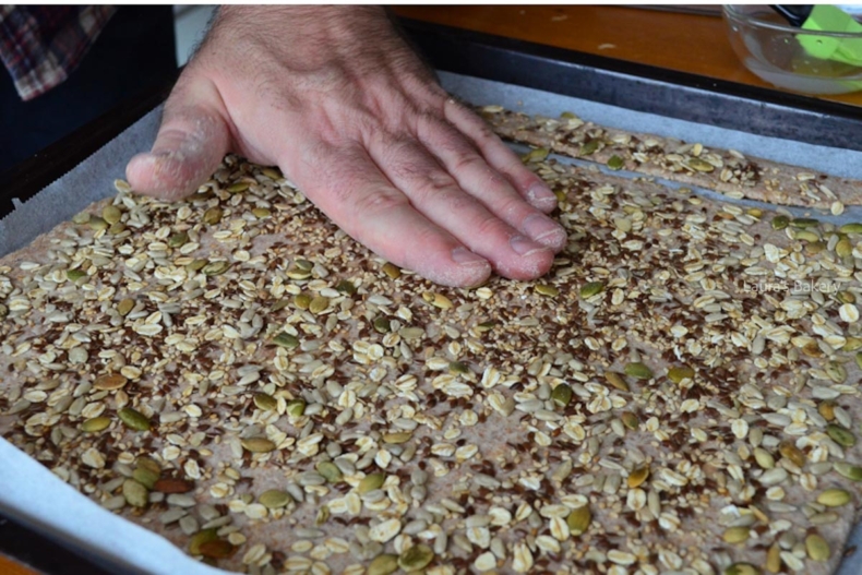 Pressing toasted seeds onto the top of the spelt cracker dough before baking