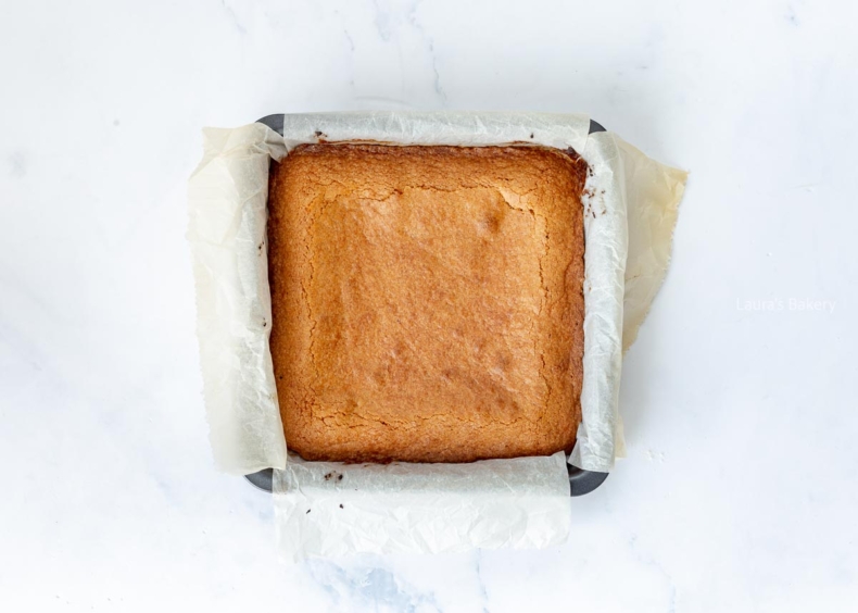 Baked blondies in a parchment-lined baking dish.